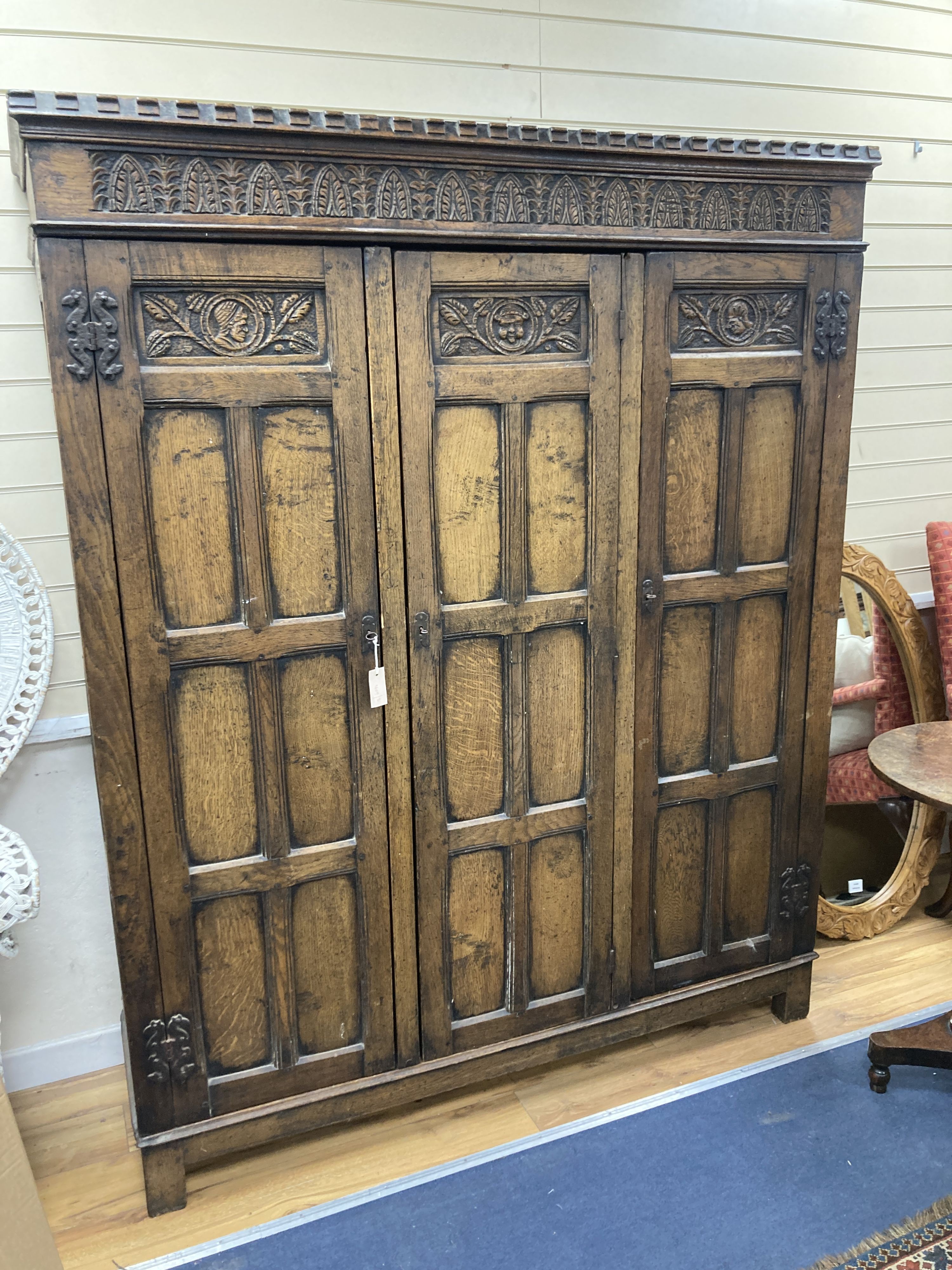 An 18th century style panelled oak triple wardrobe. W-154, D-48, H-193cm.